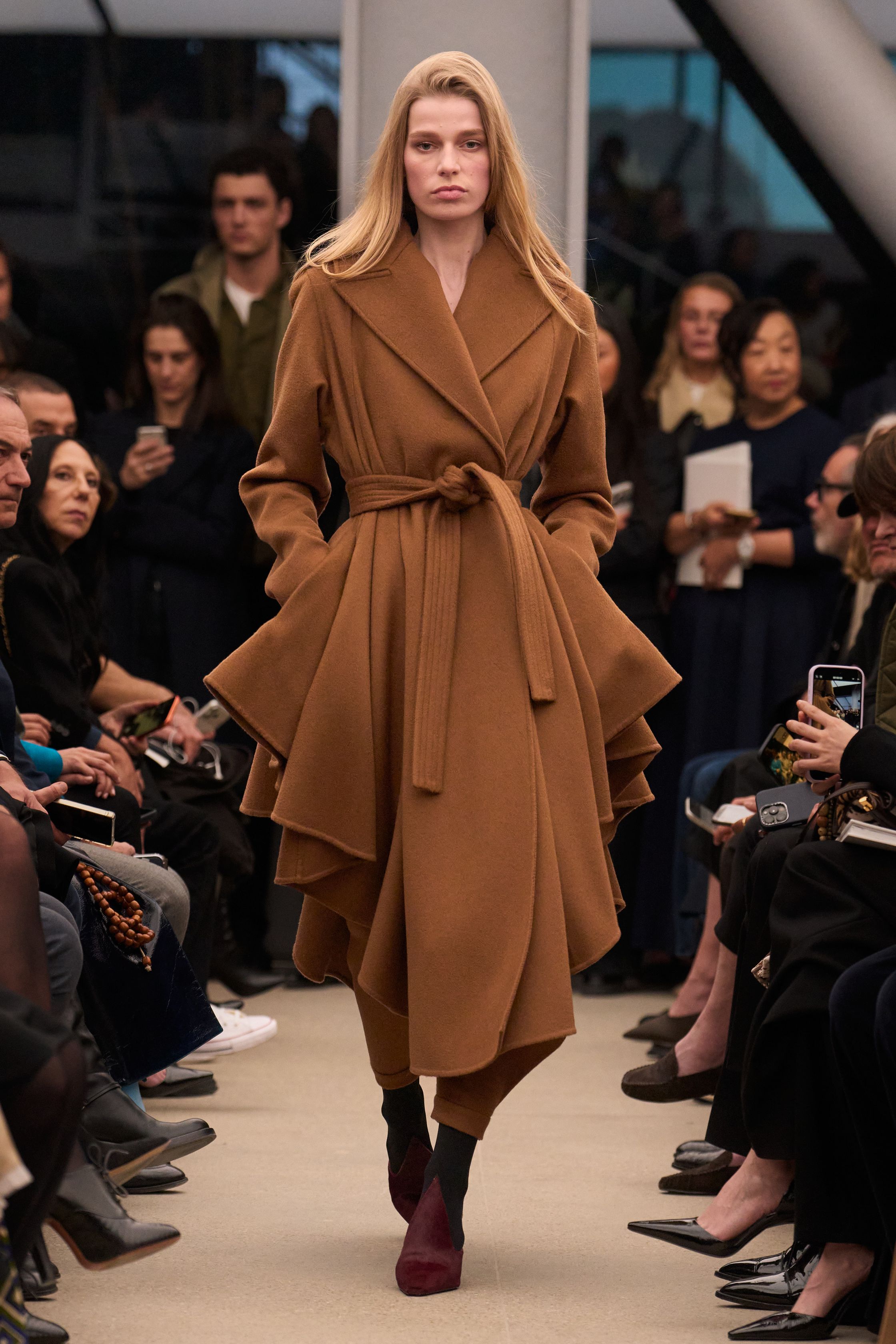 Alaïa继续以雕塑般的女性身体线条为核心，呈现极致精准的剪裁与材质张力。贴身针织长裙、立体外套与收腰大衣展现品牌标志性的曲线美学，整体色调以米色、酒红与深棕为主，营造出沉稳而性感的高级氛围。轮廓简洁却充满力量，既强调女性身体曲线，又通过结构性裁剪赋予服装雕塑般的建筑感，让极简主义与性感力量达到平衡-顽石频道趋势研究